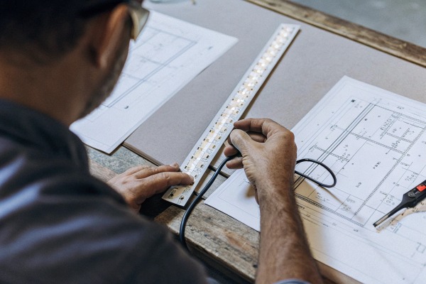 Measuring LED strip Man measuring LED strip on blueprint (ID#3)