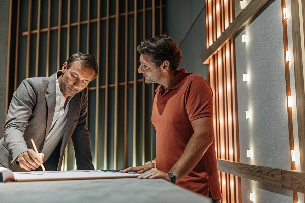 Two men discussing plans near illuminated wall panels (ID#5)